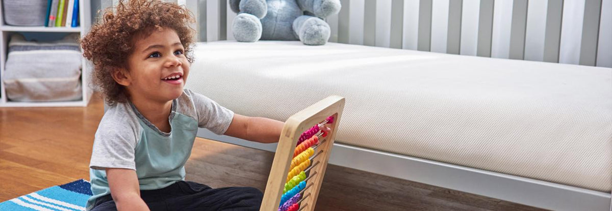 toddler playing next to big kid bed