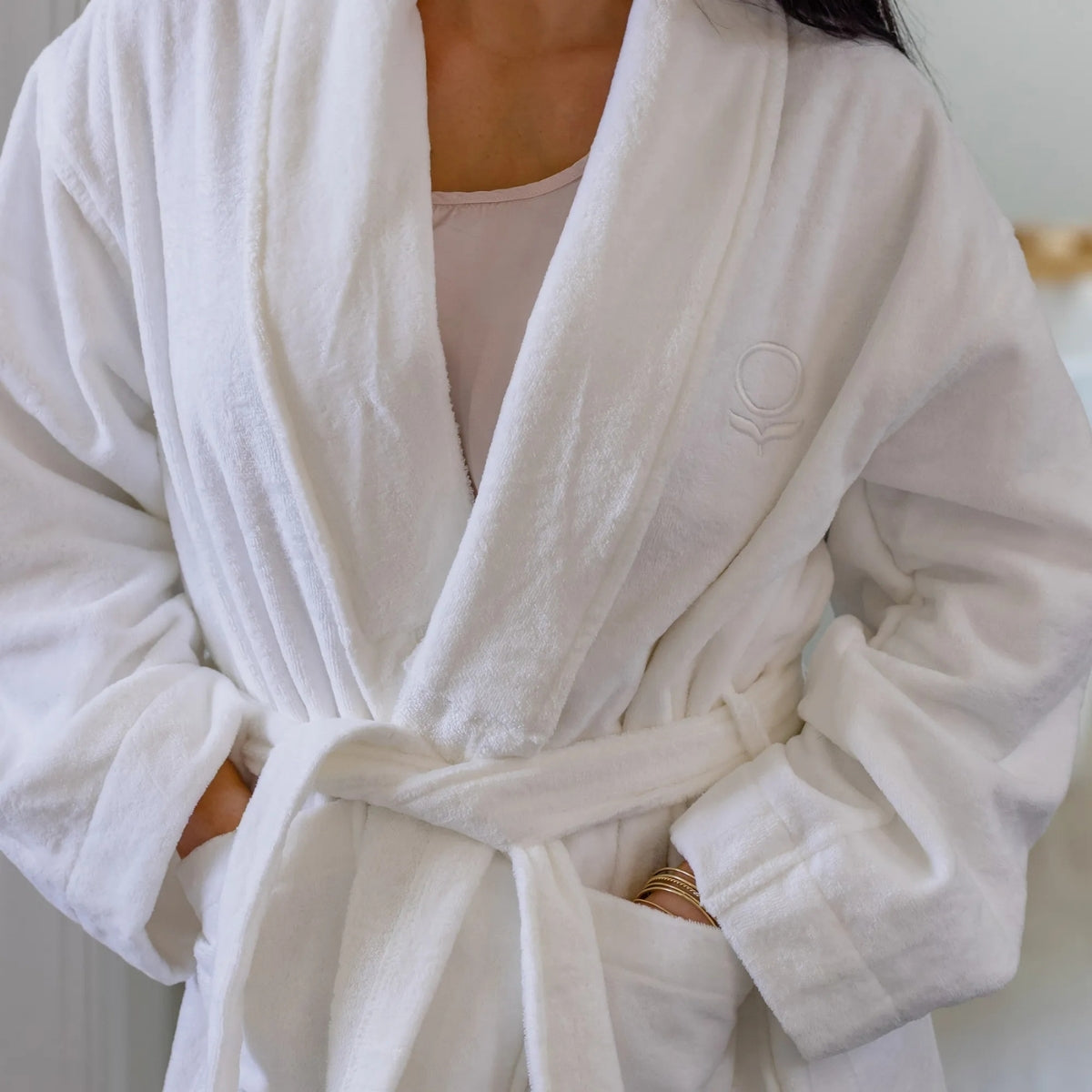 White robe with a brand logo worn by a person, against a neutral background