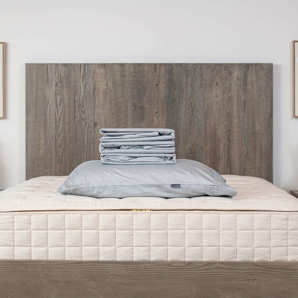 Bare mattress on a bed with wooden headboard and white walls