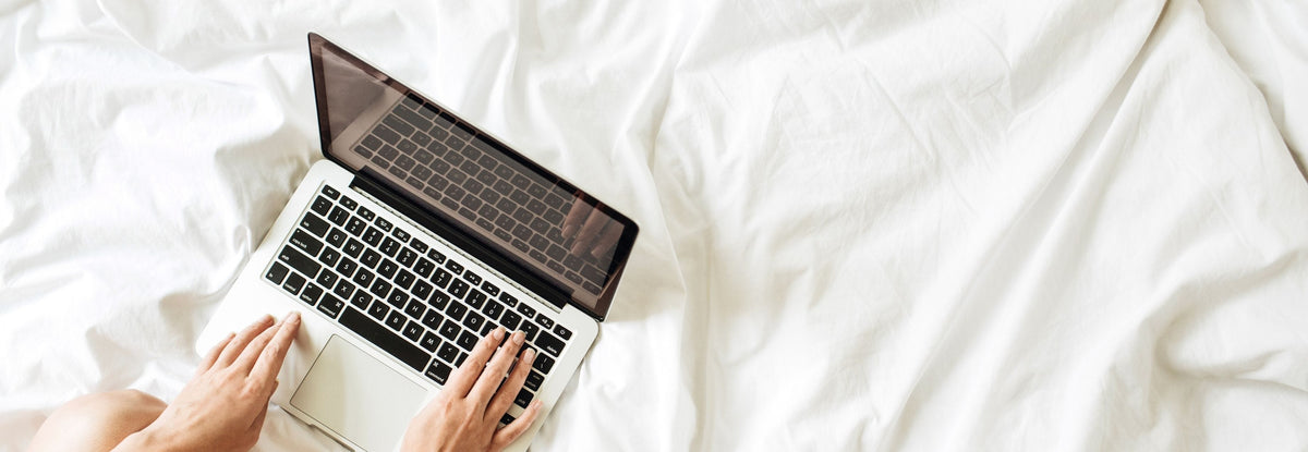person researching trends on laptop in bed