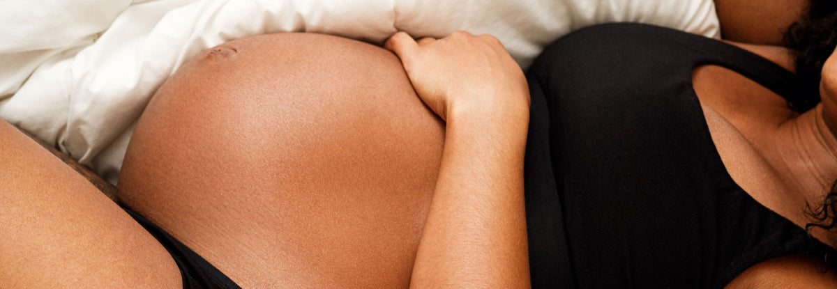 Pregnant woman propped up on pillows, trying to sleep