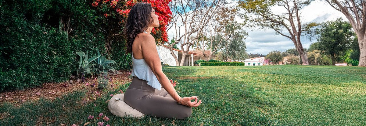 woman meditating outside on a naturepedic meditation cushion