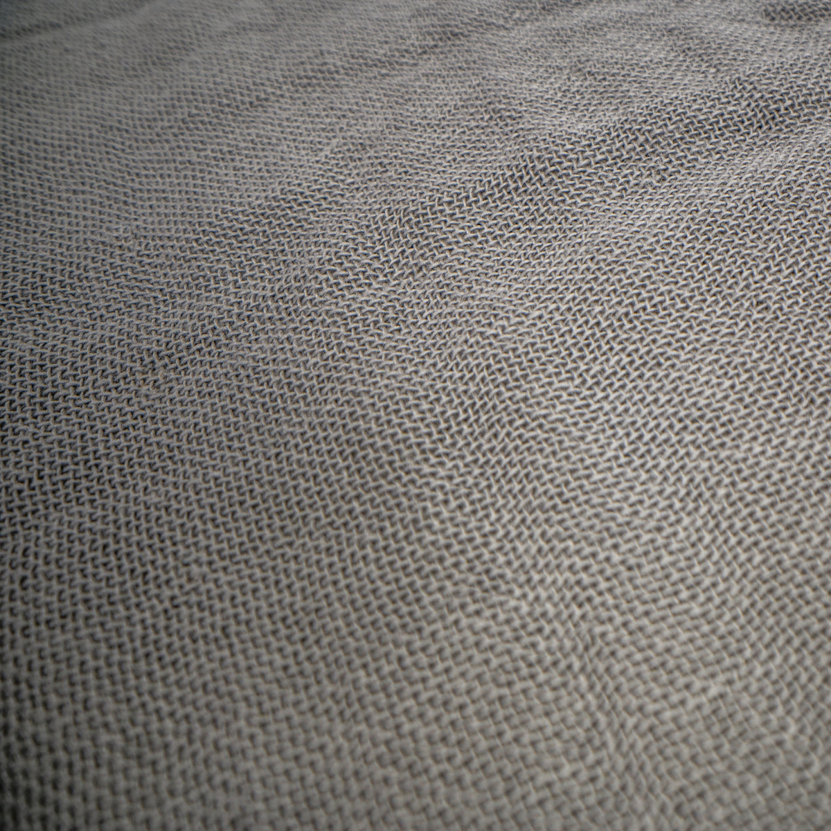 A close-up of a woven fabric texture in a medium gray color, showing the detailed knit pattern.