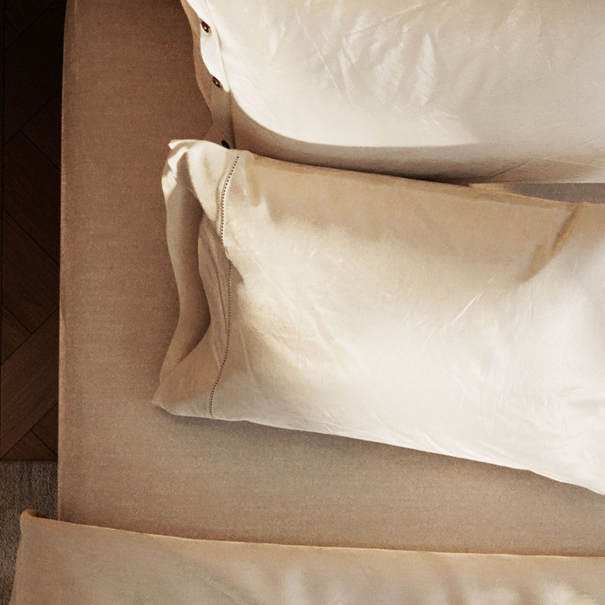 Close-up of beige pillows on a bed with a neutral color scheme.
