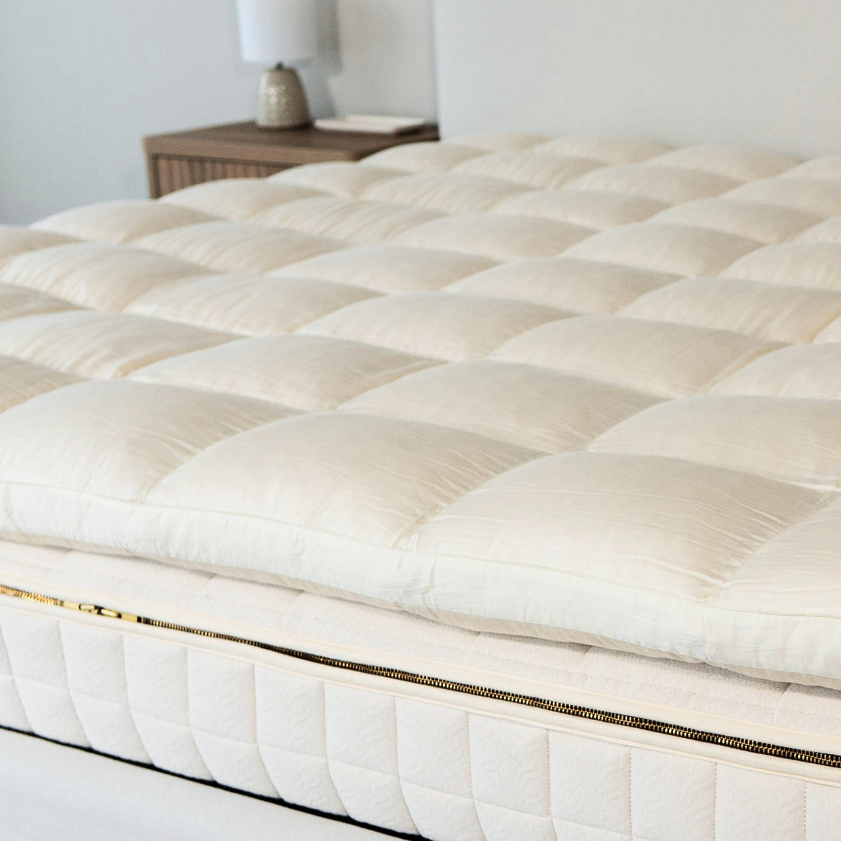White quilted mattress topper on a bed in a bedroom setting.